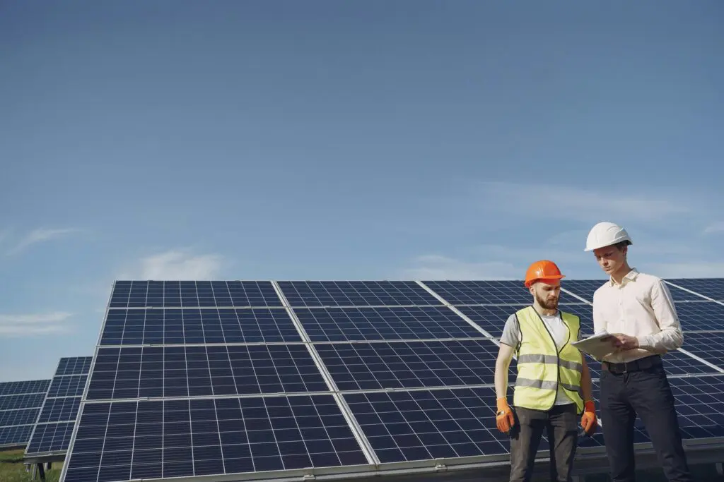 Two men standing next to a solar panel.