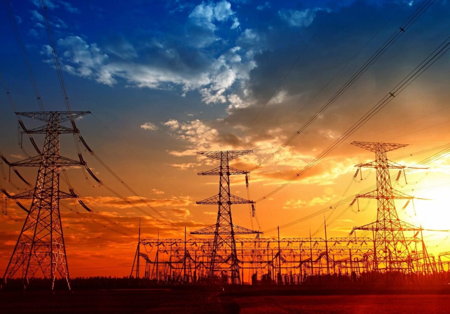 A sunset with power lines and wires in the foreground.